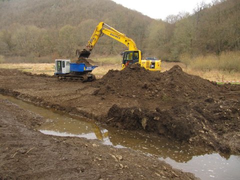 Verladen des Erdaushubs auf einen Kettendumper zum Abtransport über die Baustrasse.