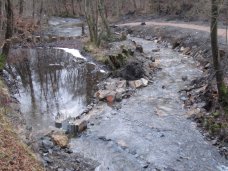 Nach dem Umbau, Dezember 2016: Die neue Bachschleife rechts im Bild; der Trenndamm mit Schieber und abgesenkten Steinen ermöglicht die Regulation der Wasserzufuhr in den Mühlgraben bei mittleren Abflüssen.